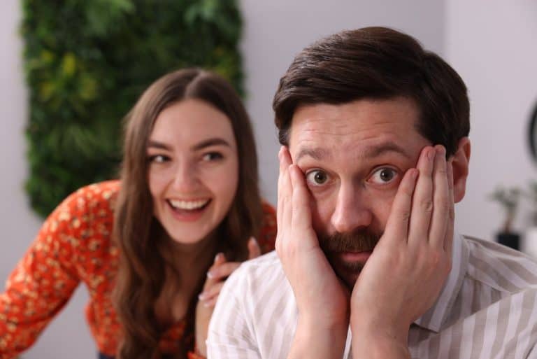 Bad date. Embarrassed man ignoring flirting woman indoors, selective focus