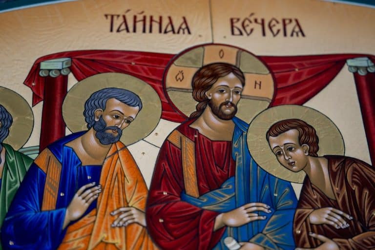 Fragment of handcrafted hot enamel orthodox icon depicting the Last Supper with Jesus Christ and apostles with golden halos.