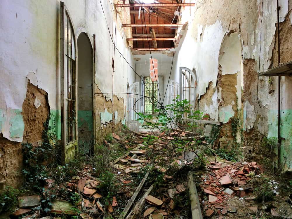 Crumbling eerie hallway inside abandoned mental institution - landscape color photo