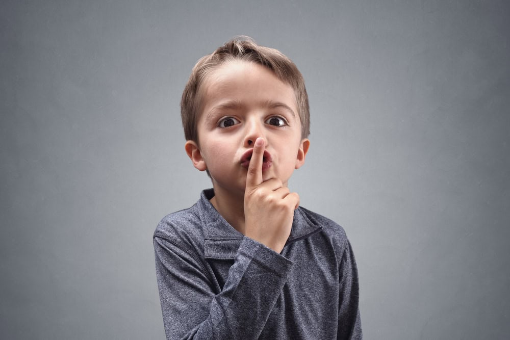 Boy with finger on lips making a silent gesture