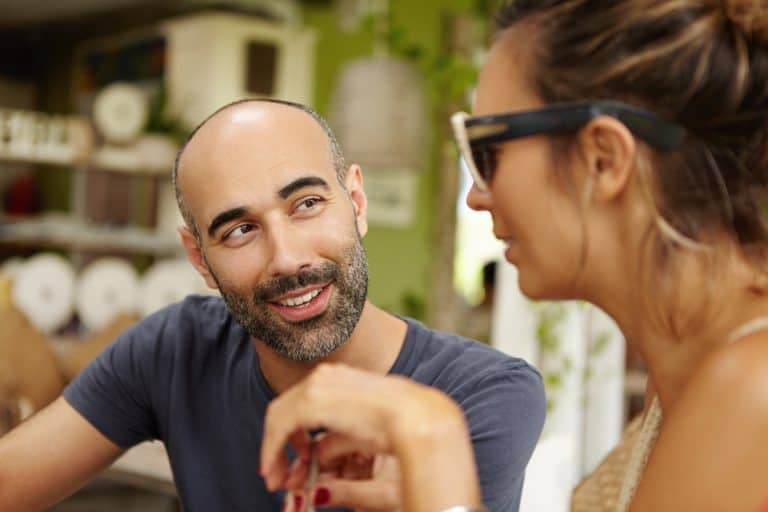 People and leisure. Lively conversation at sidewalk cafe of one adorable couple. Cheerful bearded man flirting with his attractive girlfriend in shades during lunch at outdoor restaurant on sunny day