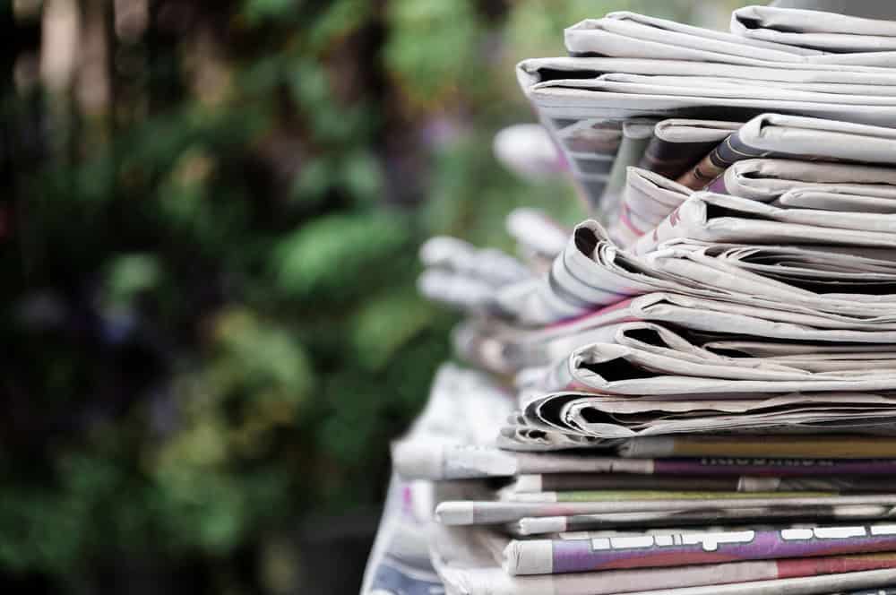 Newspapers folded and stacked on the table with garden. Closeup newspaper and selective focus image. Time to read concept.