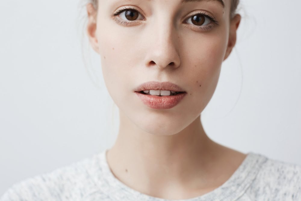 Youth, beauty and skin care concept. Close-up shot of beautiful charming young female of Caucasian appearance with porcelain pale skin and fair hair looking at camera with lips slightly parted