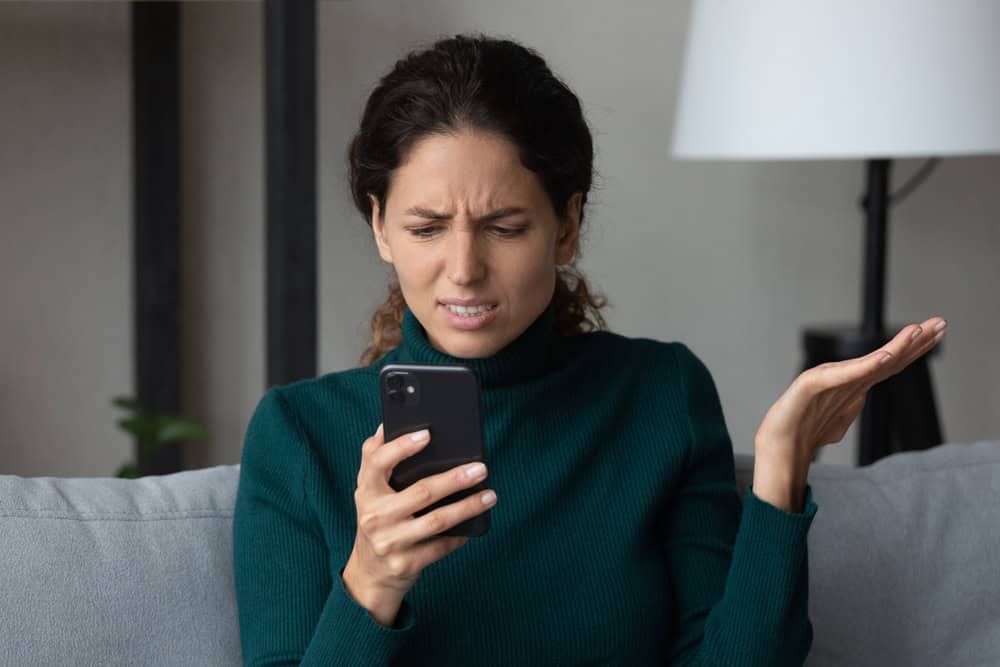 Close up angry dissatisfied woman looking at phone screen, unhappy confused young female having problem with broken smartphone or internet fraud, slow internet connection, reading bad news in message