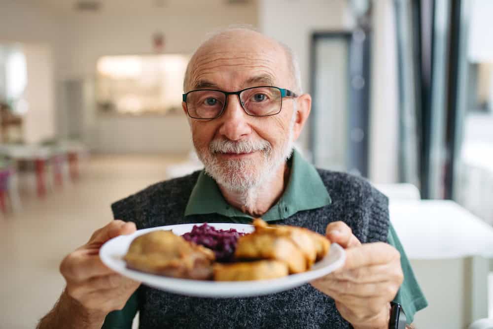 Senior man enjoying lunch at community dining hall.
