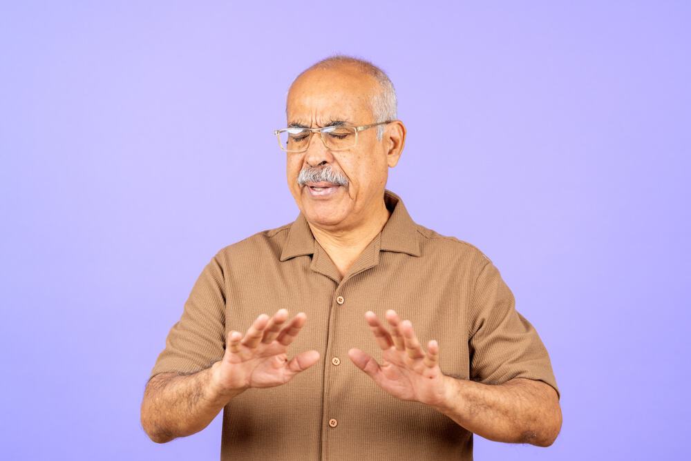 Mature man making a stopping gesture with both hands, expressing negative emotions like refusal, rejection, and discomfort