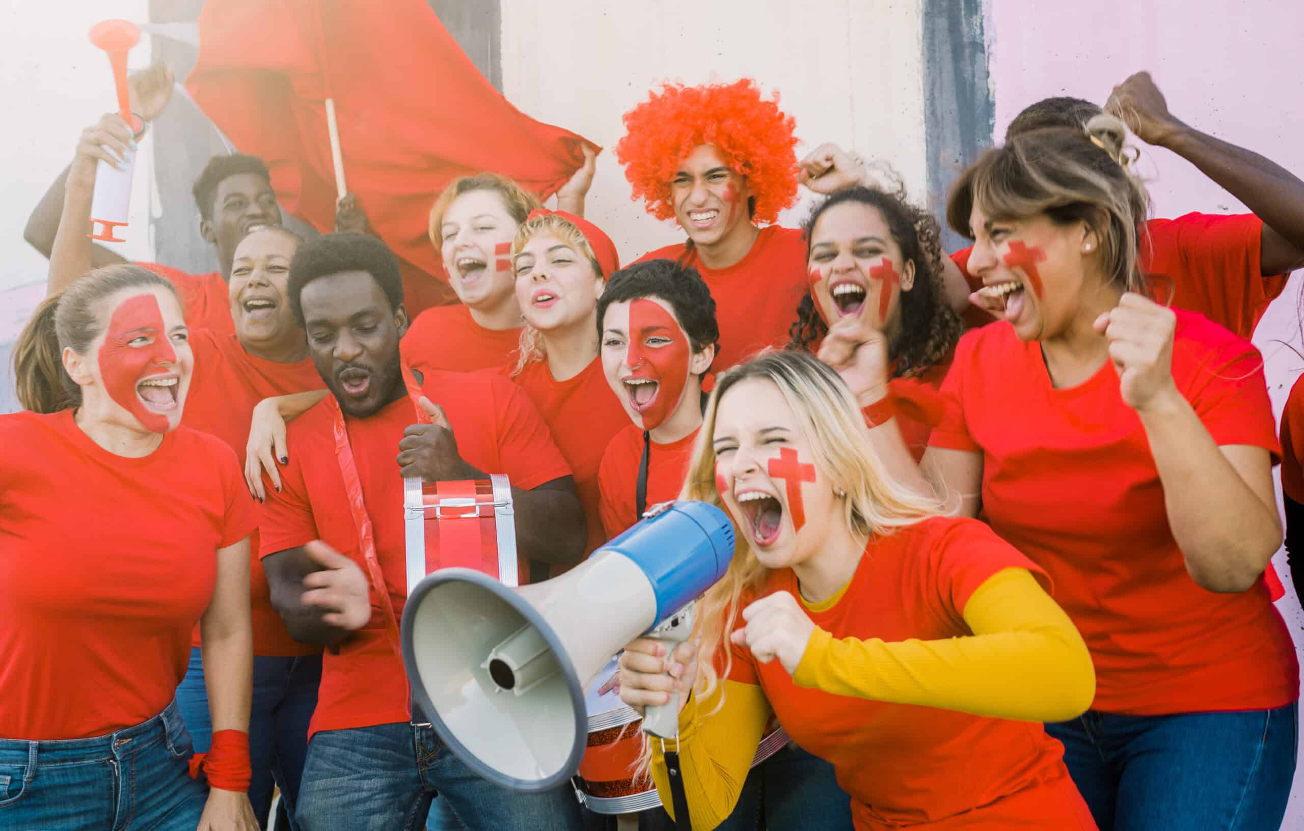 Group of joyful diverse fans screaming during football match