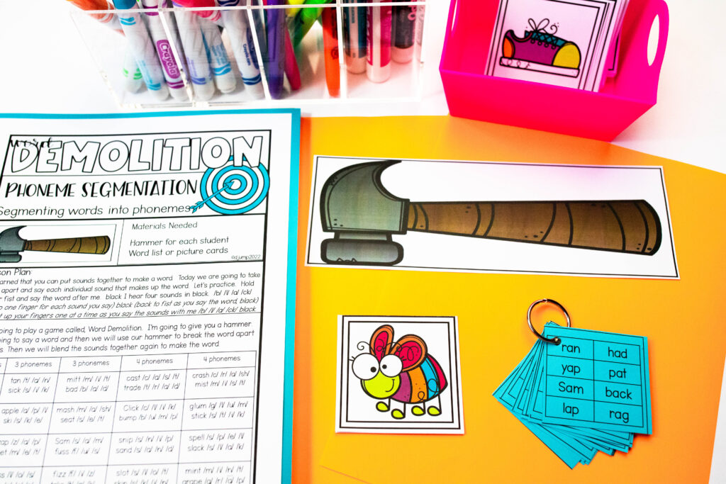 A paper hammer and picture card sit next to lesson plans for a phoneme segmentation activity