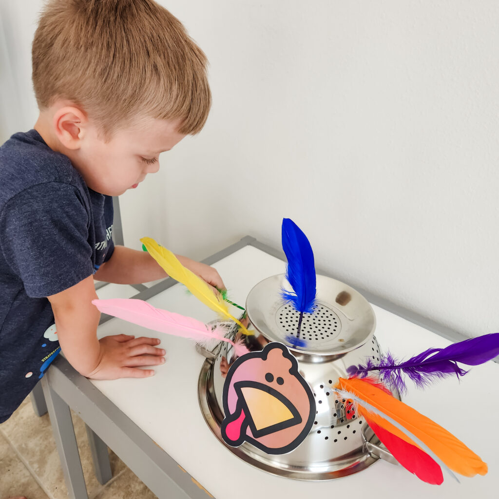 A boy adds colorful feathers to the holes of a colander