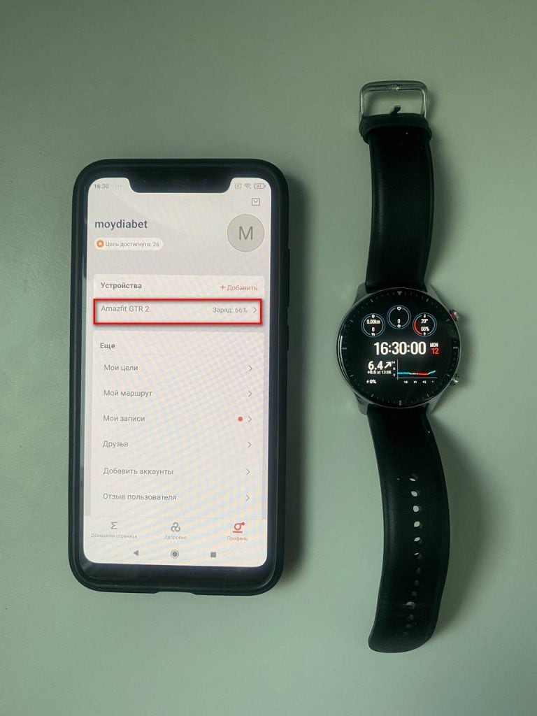 Смарт-годинник і смартфон з додатком для моніторингу цукру в крові на світлому фоні.