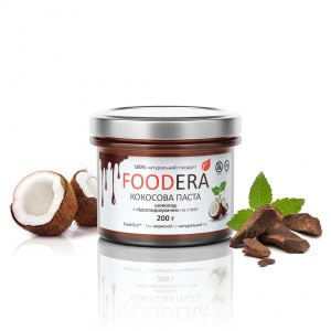 Баночка кокосово-шоколадної пасти без цукру Foodera на фоні шматочків кокоса та какао-бобів