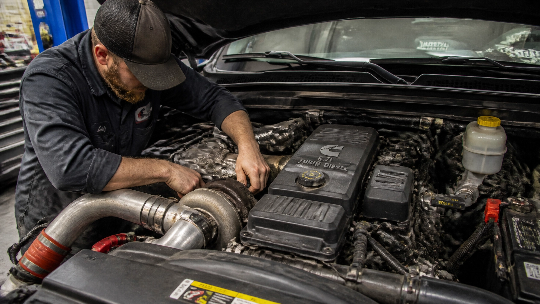 Mechanic working on a vehicle engine at Dirty D’s Performance shop.
