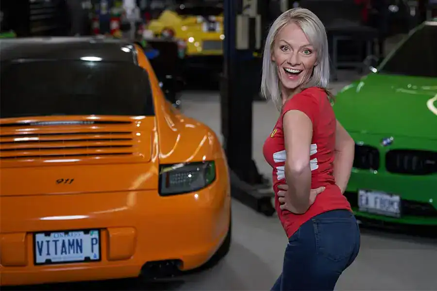Woman smiling at camera with colorful sports cars in the background.