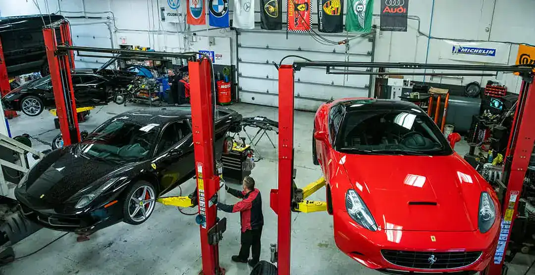 Luxury sports cars being serviced in a professional automotive workshop.