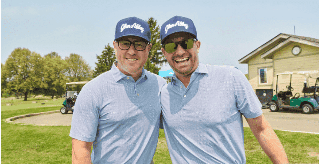 Two men in golf attire smiling at the golf course.