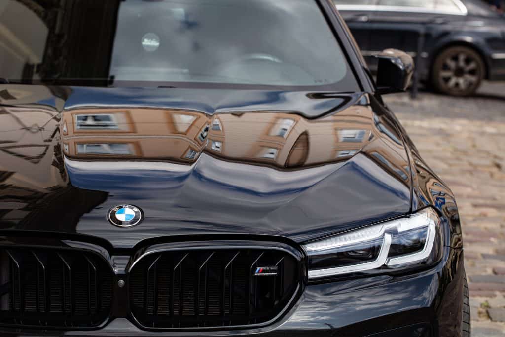Close-up of a black BMW car front with reflections on the hood.