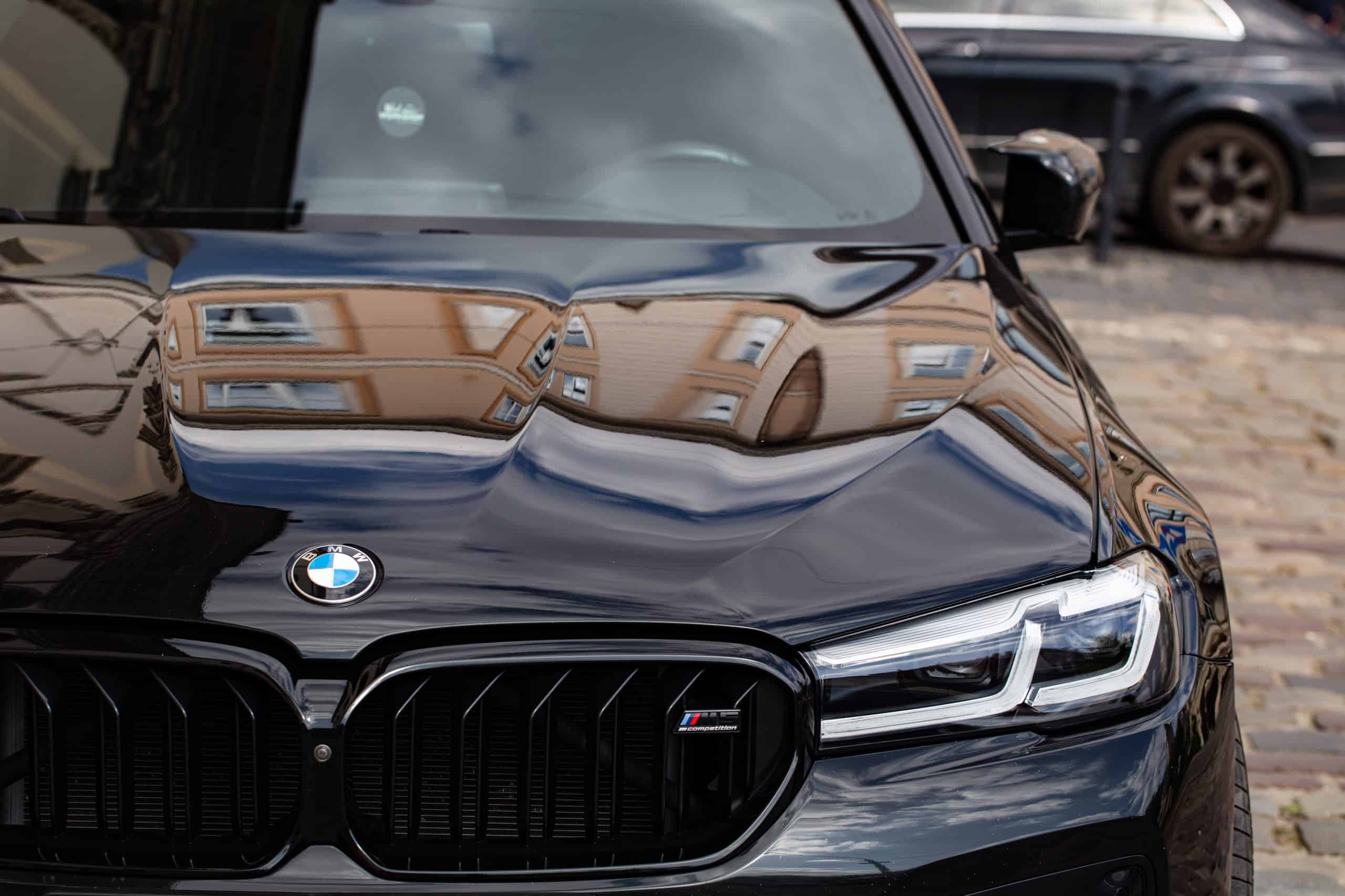 Close-up of a black BMW car front with reflections on the hood.