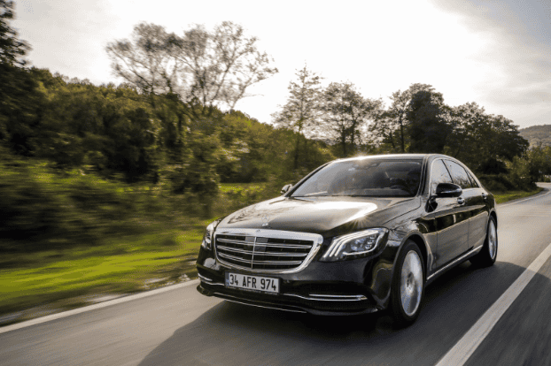 Black luxury Mercedes-Benz driving on a scenic road in Europe.