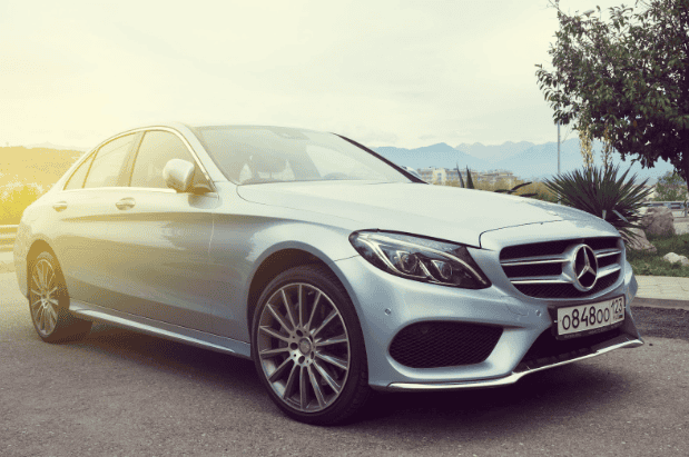 Silver Mercedes-Benz sedan parked outdoors with mountains in background.
