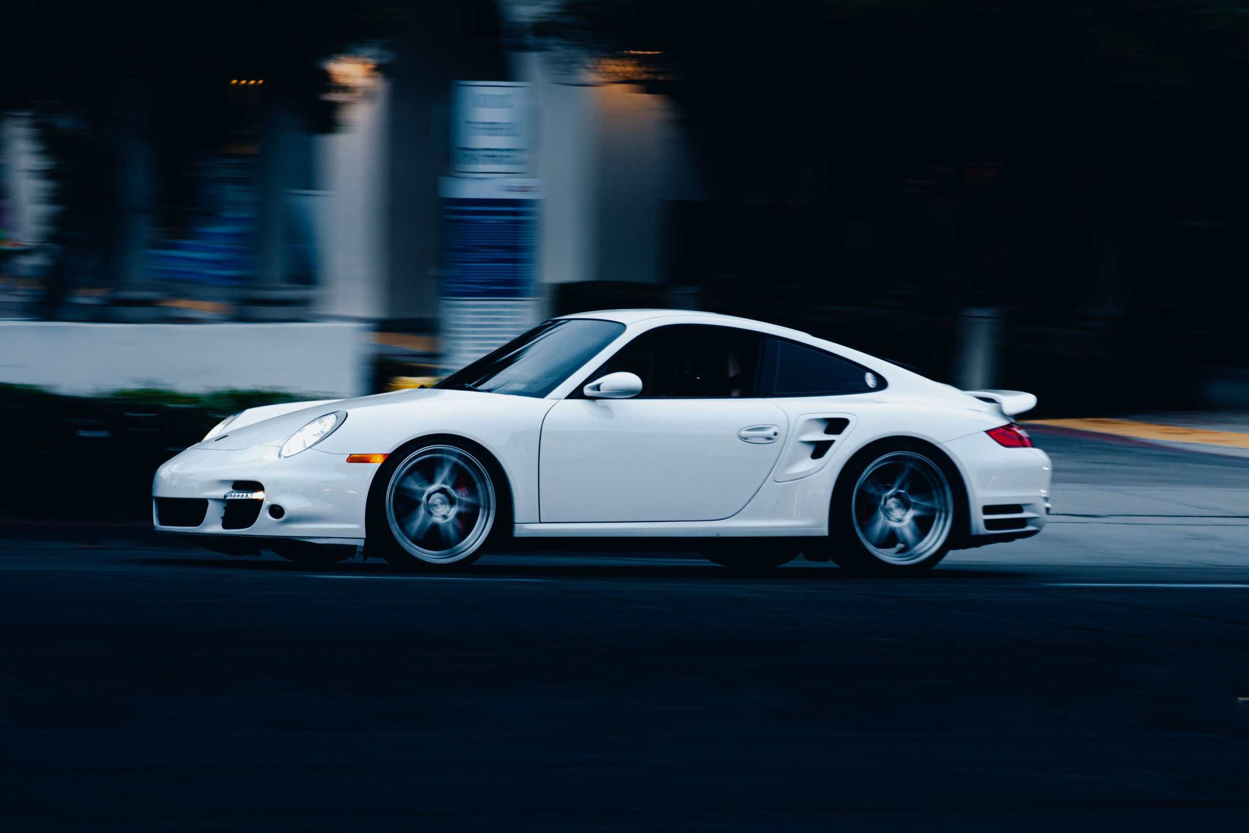 White sports car driving on city street at night.