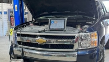Auto repair technician diagnosing vehicle engine in Dallas, Texas.