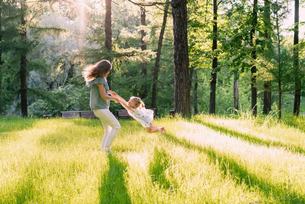 Family playing in a sunny, green park in Lakeway, Texas, surrounded by tall trees and vibrant grass.
