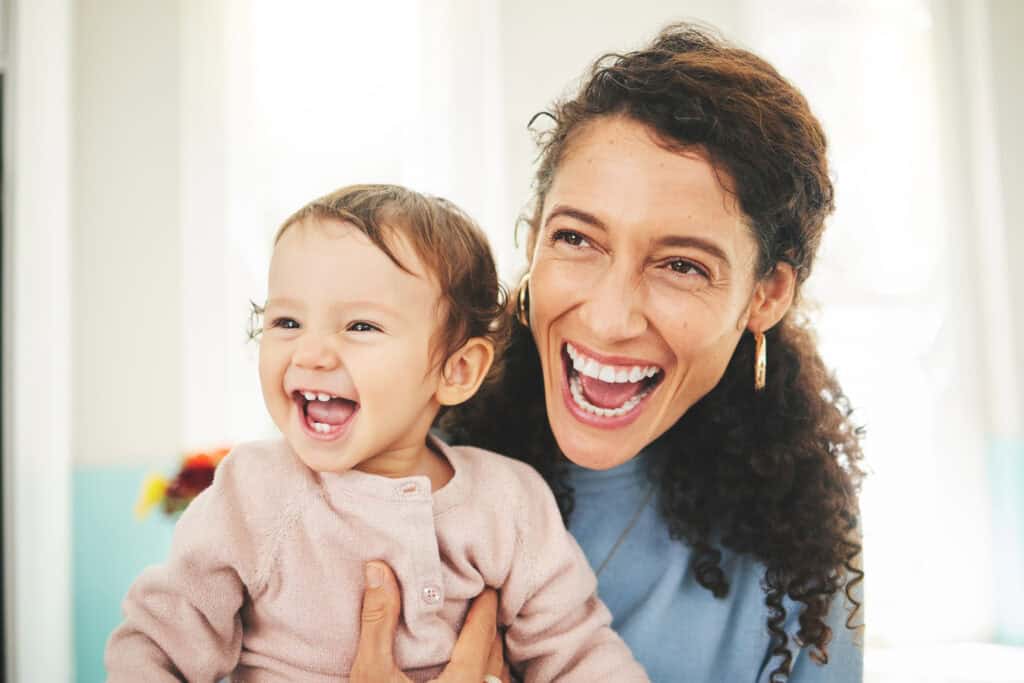 Happy mother holding her smiling toddler girl, enjoying quality time indoors.