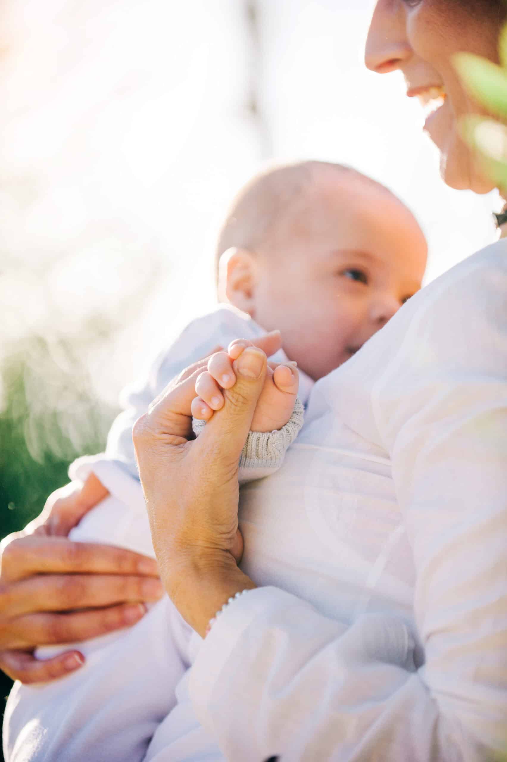 Mother holding her baby close, sharing a tender moment in a peaceful outdoor setting.