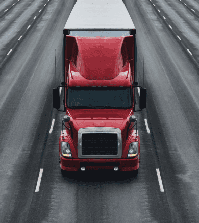 Red cement mixer truck on an open highway, ready for construction work.