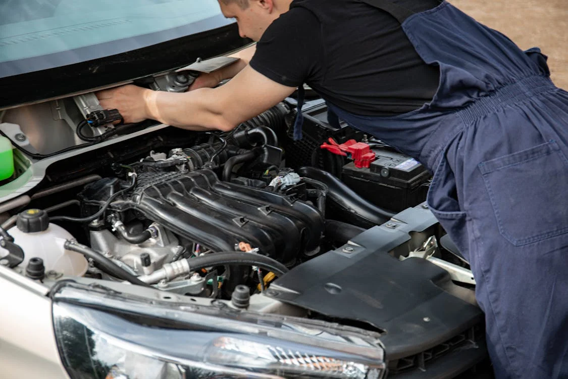 Auto mechanic inspecting car engine for safety and performance.