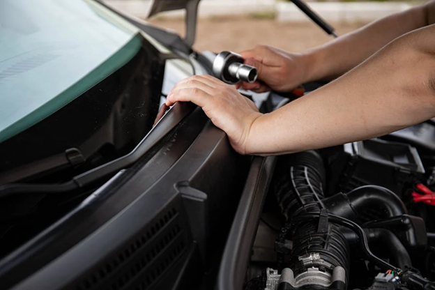 Technician inspecting a car engine during maintenance service.