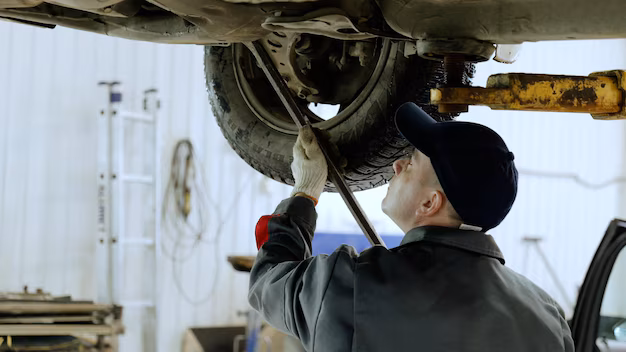 skilled-automotive-technician-checking-vehicle-undercarriage-with-pry-bar-wearing-protective-gear_1175976-1742.avif