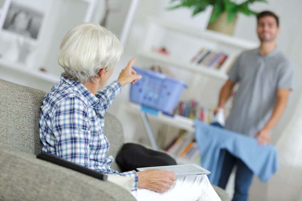 Elderly Lady Talking To Man Ironing