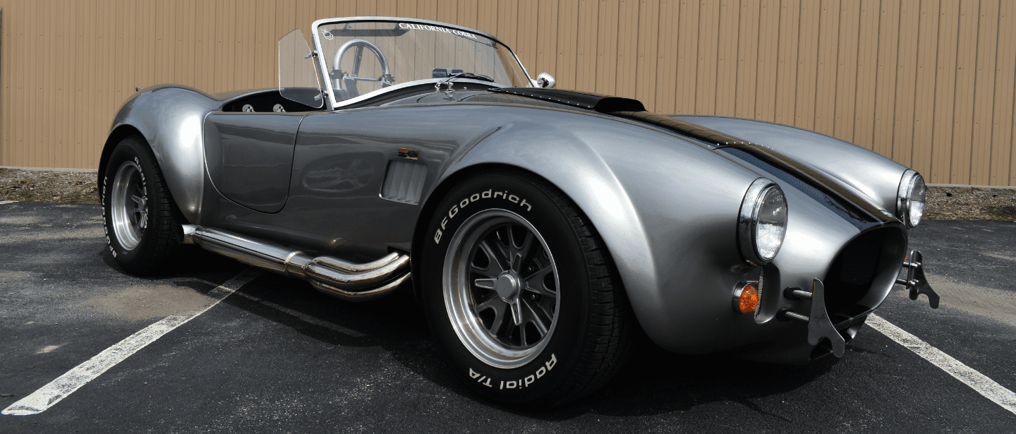 Vintage Shelby Cobra sports car in silver, showcasing expert restoration work.