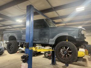 Automotive restoration shop showcasing a lifted vintage truck in progress.
