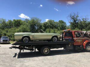 Vintage convertible car being transported on a flatbed tow truck.