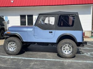 Off-road vehicle with blue body and black soft top at John's Auto Restoration.