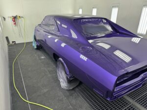 Restored purple classic car in a professional auto body shop.