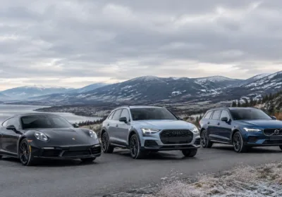 Three luxury cars parked on mountain road with scenic background.