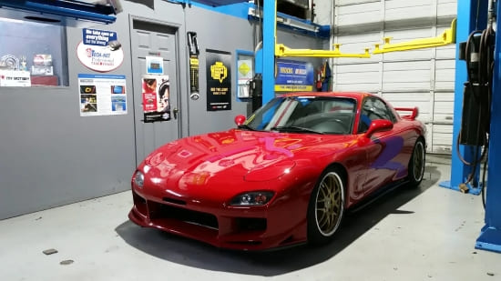 RX-7 sports car in a garage setting, showcasing sleek red exterior and performance design.