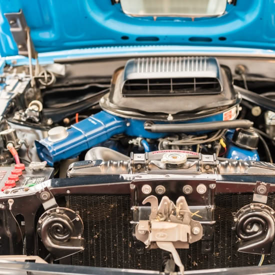 Close-up of a classic American car engine at Schimpfs Garage, showcasing detailed mechanical compone.