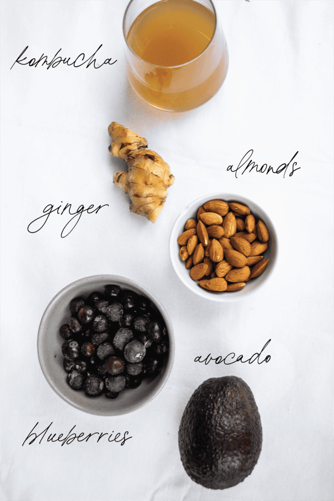 Almonds, blueberries, ginger, avocado, and kombucha on a white surface, healthy superfoods, fresh ingredients for smoothies or snacks.