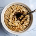 Creamy coconut rice pudding topped with toasted coconut flakes and a dollop of rich chocolate sauce in a white bowl.