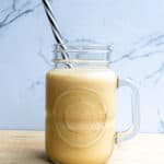 Creamy smoothie in a mason jar with a striped straw, perfect for healthy eating and fresh food recipes.