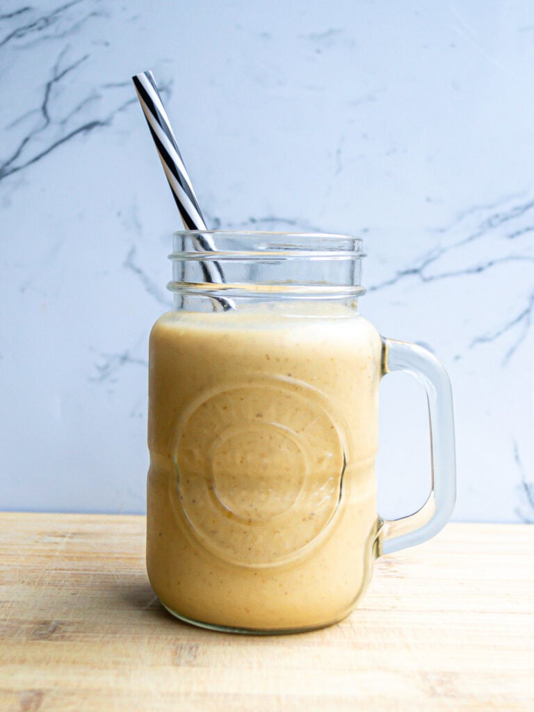 Creamy smoothie in a mason jar with a striped straw, perfect for healthy eating and fresh food recipes.