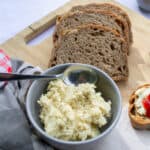 Buttered whole grain bread slices on a wooden cutting board with a bowl of creamy mashed potatoes, perfect for hearty breakfast or nutritious meal.