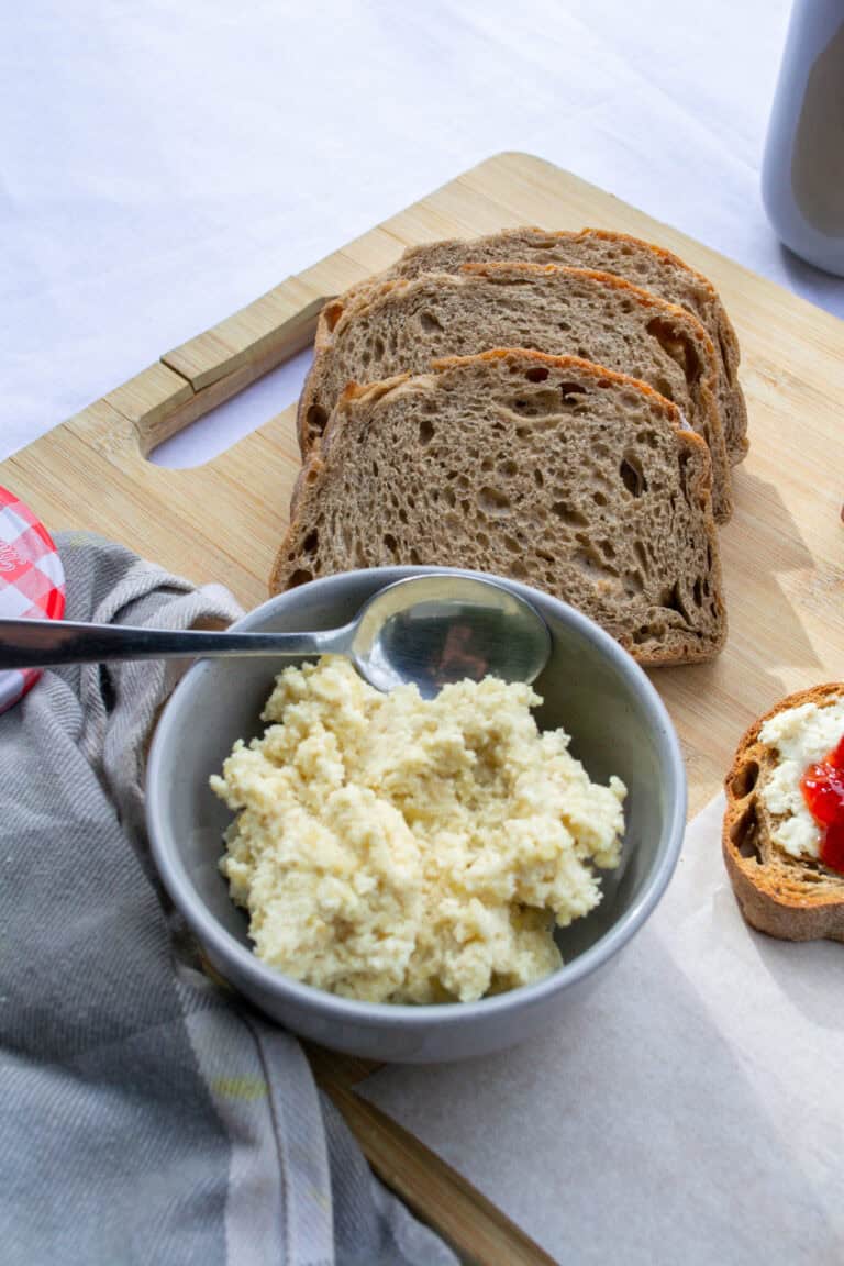 Buttered whole grain bread slices on a wooden cutting board with a bowl of creamy mashed potatoes, perfect for hearty breakfast or nutritious meal.