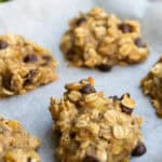 Chewy oatmeal chocolate chip cookies with oats and melted chocolate chips, fresh out of the oven on parchment paper. Perfect for healthy snacking or satisfying a sweet tooth with wholesome ingredients.