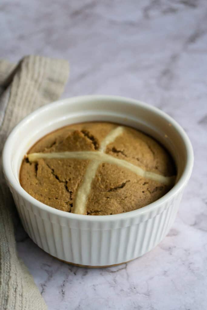 Fudgy cookies in a white ramekin, topped with almond slices, placed on a marble surface with a beige cloth nearby.