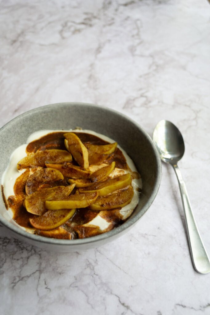 Apple pie overnight weetabix in a bowl with a spoon next to it.